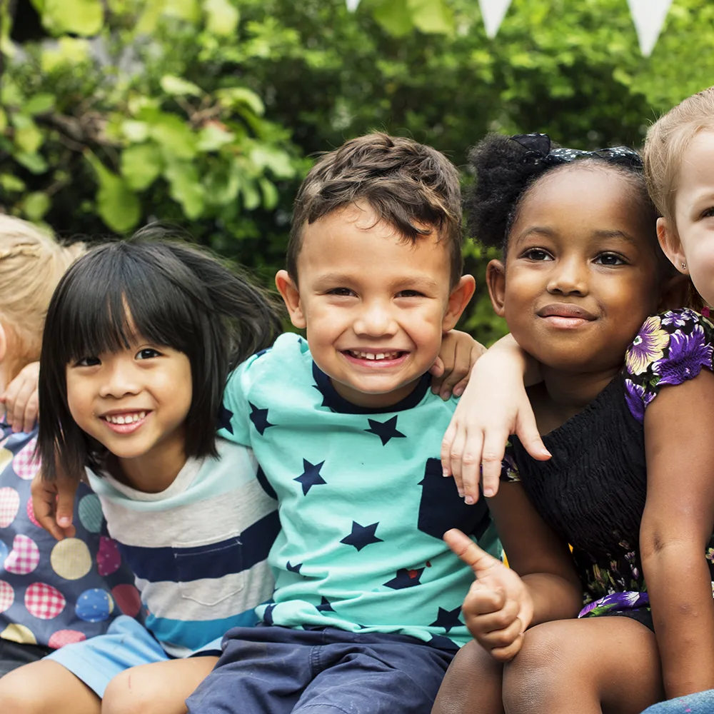 A group of children smiling outside of a Peace of Mind daycare