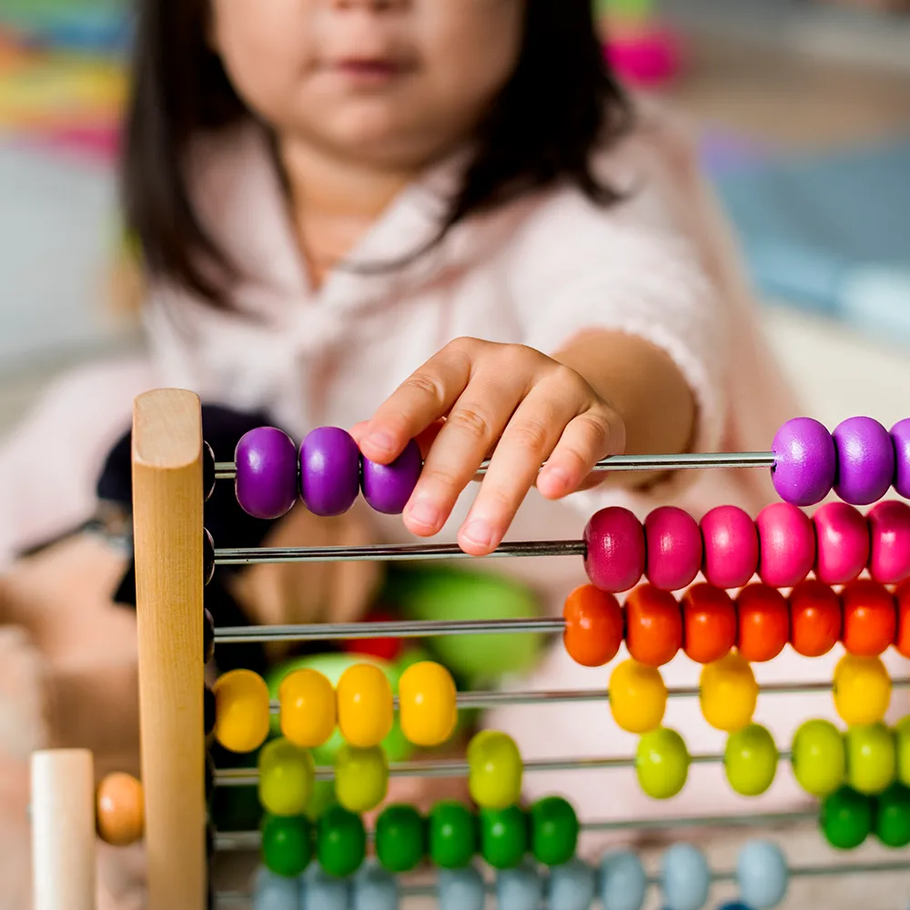 A child working with beads on an abacus at Peace of Mind daycare