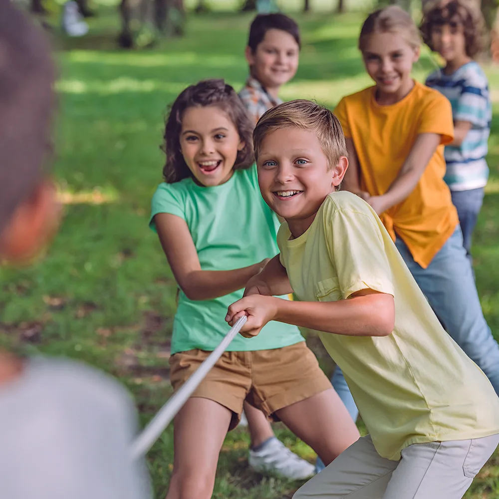 A group of children playing tug of war during summer camp at a Peace of Mind daycare