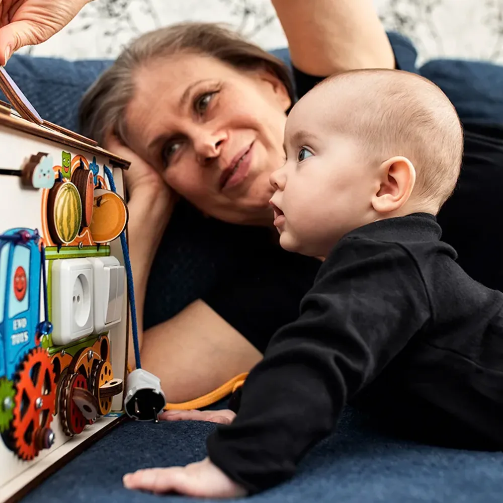 A teacher showing an infant a play box on the floor at a Peace of Mind daycare