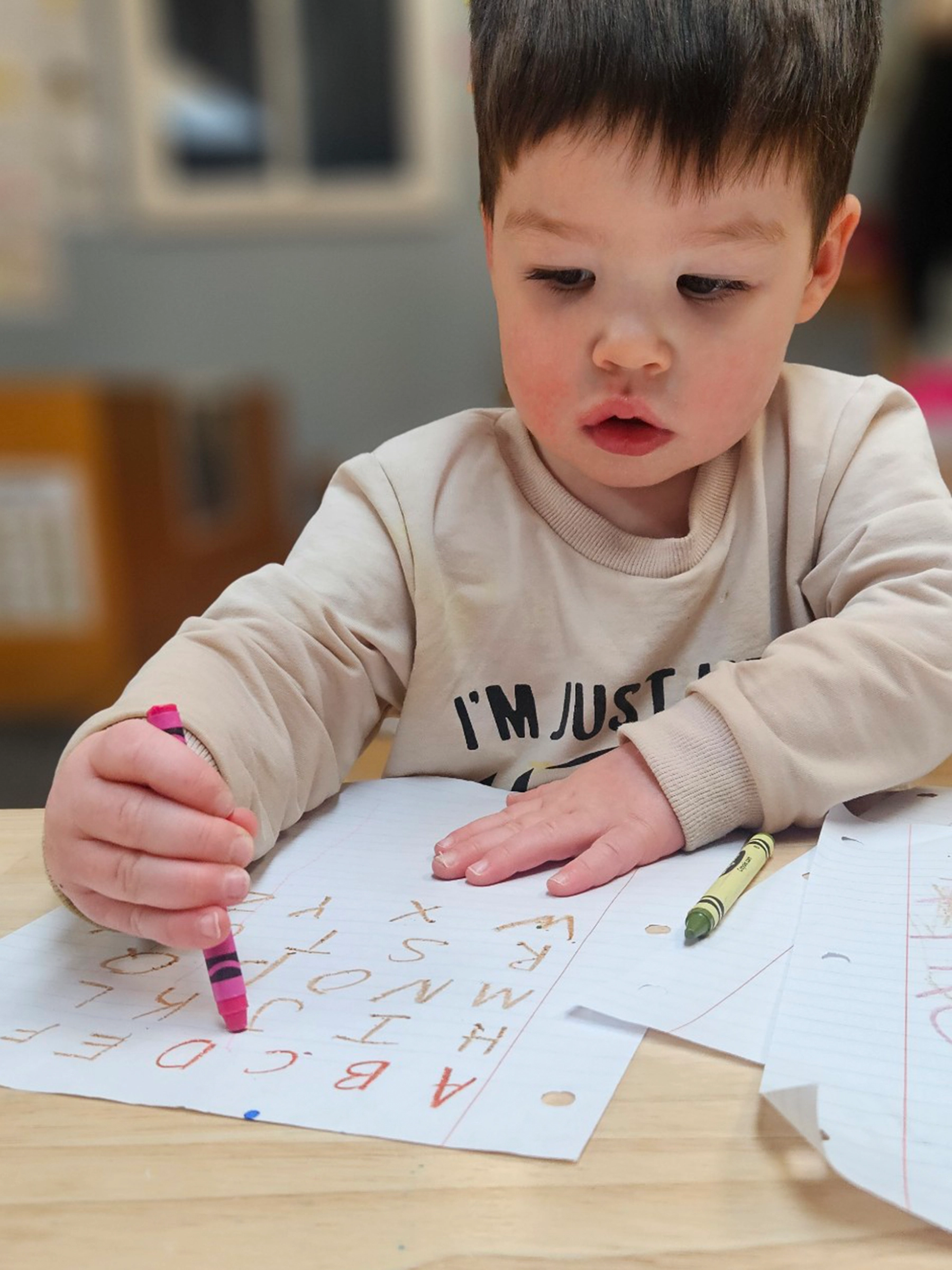 Child coloring the alphabet at a table at Peace of Mind daycare.
