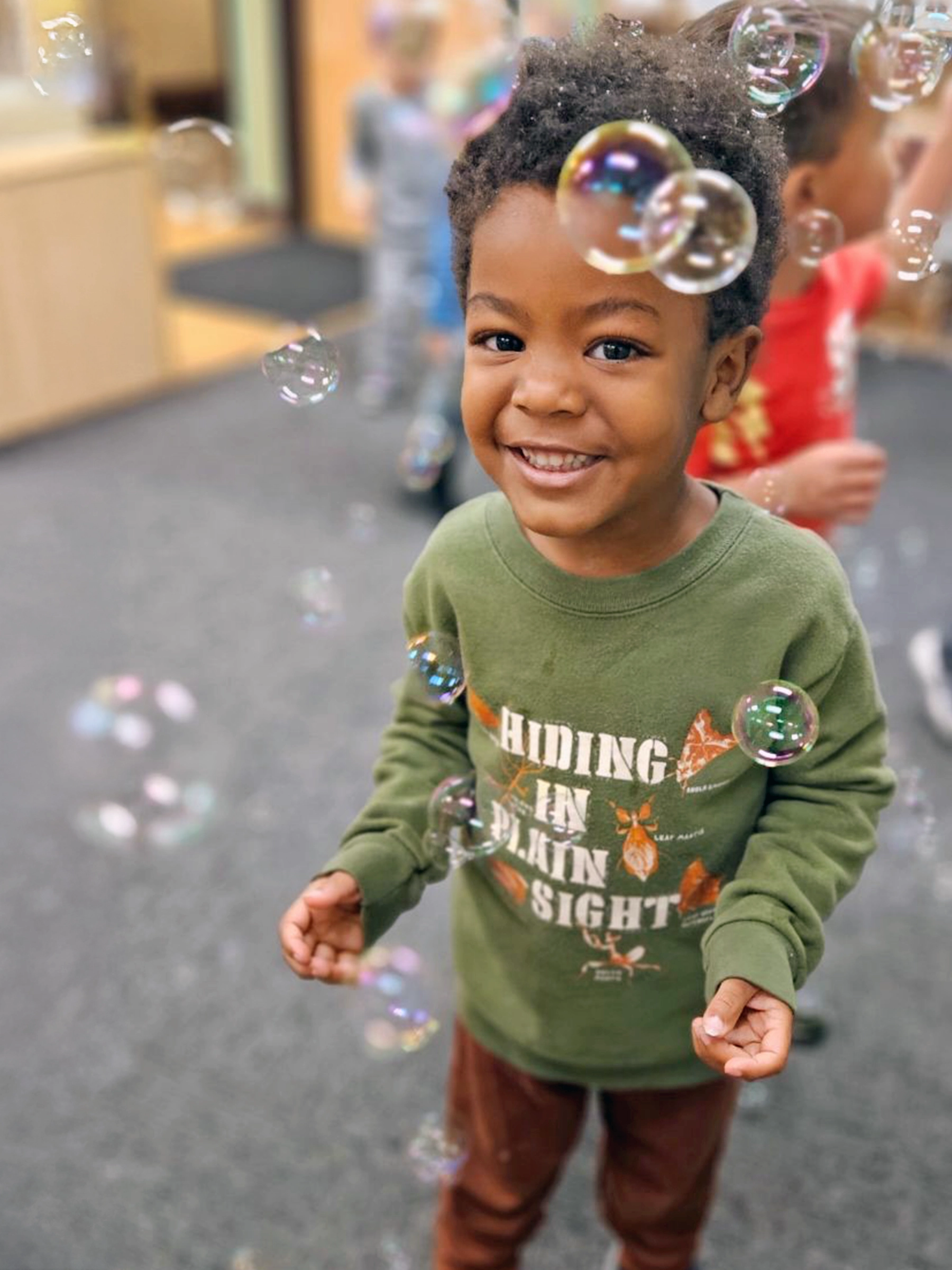 Child standing among floating bubbles at a Peace of Mind daycare.