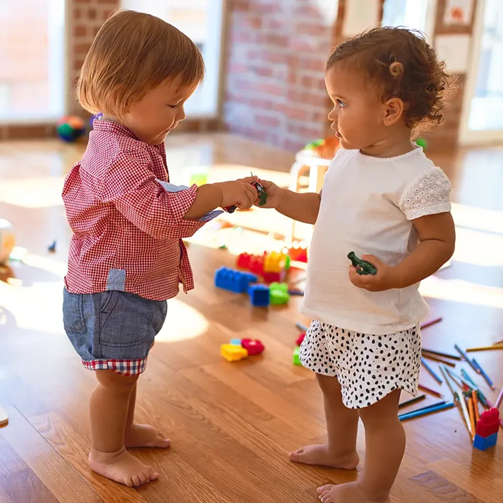 Two toddlers sharing toys at a Peace of Mind daycare