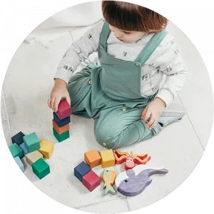 A child playing with blocks on the floor at a Peace of Mind daycare